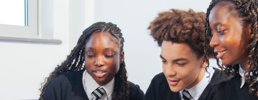 Happy learners in in a classroom with Wave 3 text on a neon pink shape