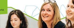 Smiling staff with geometric shape outlines in the background and text: Made for Wales.