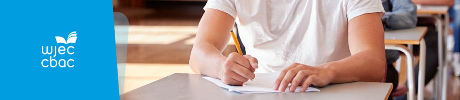 Close-up of learner sitting in a hall and writing in an exam paper.
