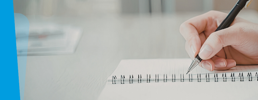 Close-up of hands writing in a notebook.